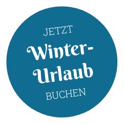 Runder, blauer Button mit der weißen Aufschrift "Jetzt Winterurlaub buchen"